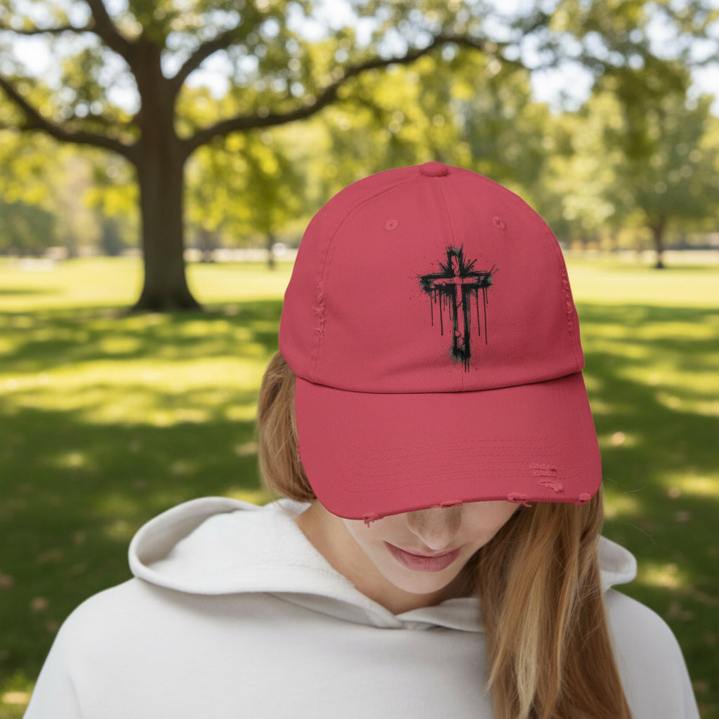 Red cap with black cross design worn by a person on a white background