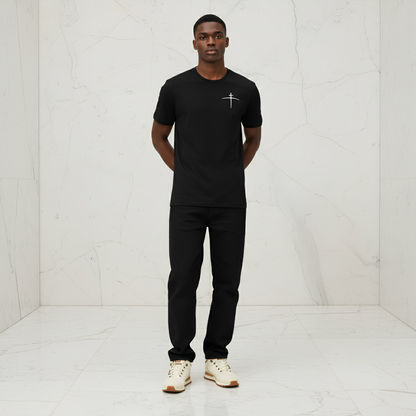 Man wearing a black t-shirt with a logo and black pants in a white room