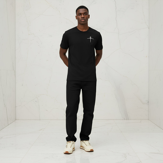 Man wearing a black t-shirt with a logo and black pants in a white room